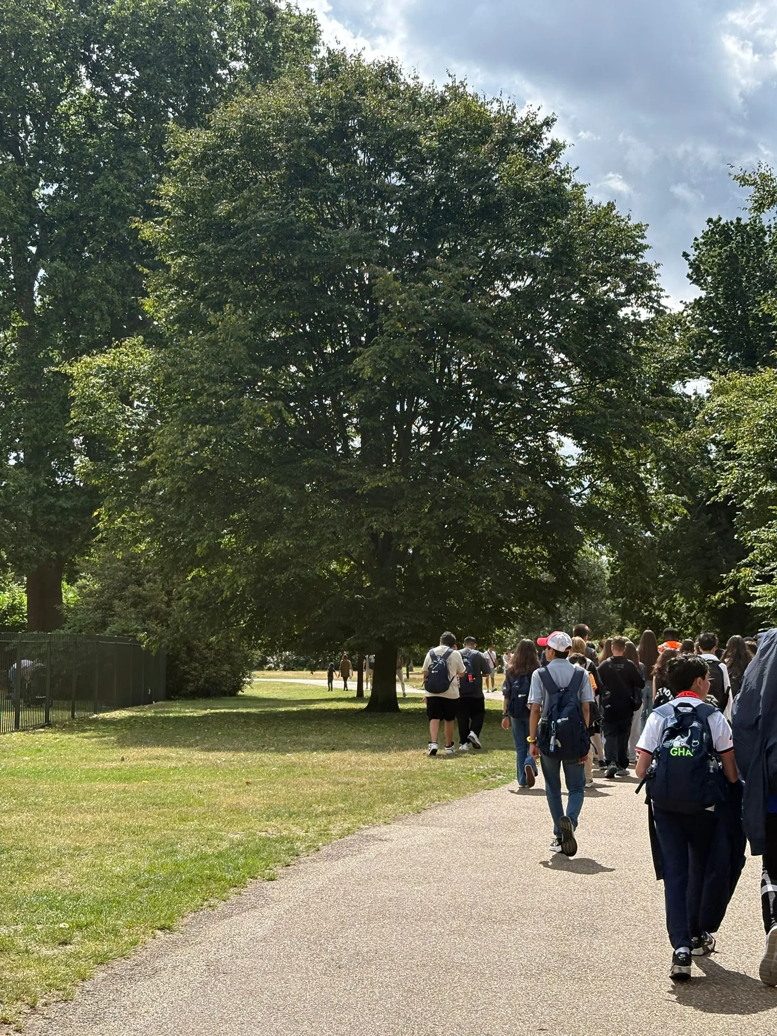 Ağaçlıklı bir park yolunda yürüyen öğrenci grubu
