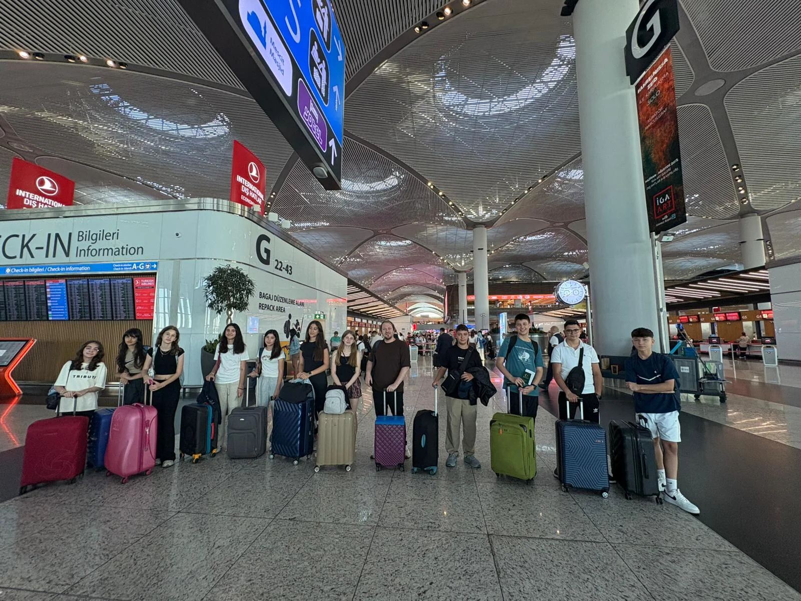 Havalimanında check-in kuyruğunda valizleriyle bekleyen öğrenci grubu